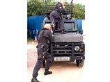 На фото один из бойцов позирует на капоте бронированного Land Rover Defender, в то время как другой целится ему в зад из дробовика. По видимому, оружие при этом не заряжено. Оба одеты в полицейскую форму и имеют при себе пистолеты Glock с боевыми патронам