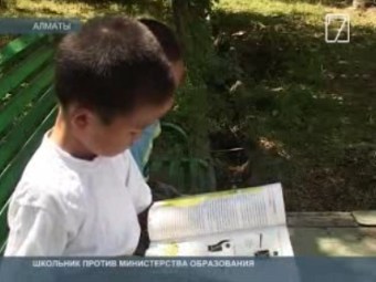 Второклассник Алихан Жуманов с учебником. Кадр "7 канала" казахстанского телевидения.