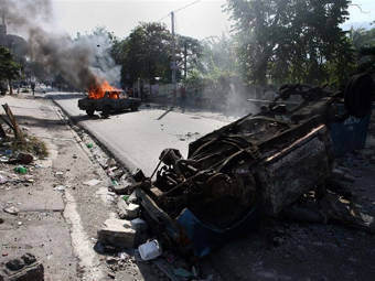 Сожженные автомобили на улице одного из гаитянских городов. Фото ©AFP